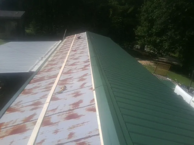 Old rusted panels beside newly installed green metal roofing — Wind Damage Roof Repair by Roofing Brothers in Burgettstown