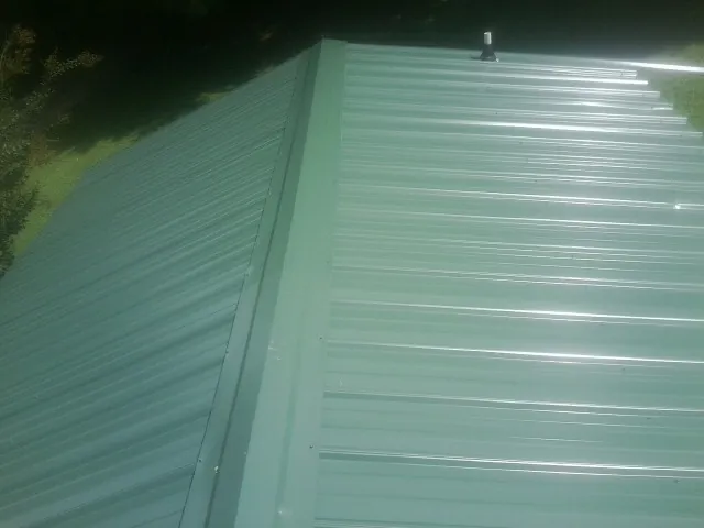 New green metal panels meeting at the ridge of a roof — Flat Roof Repair work by our crew in Burgettstown