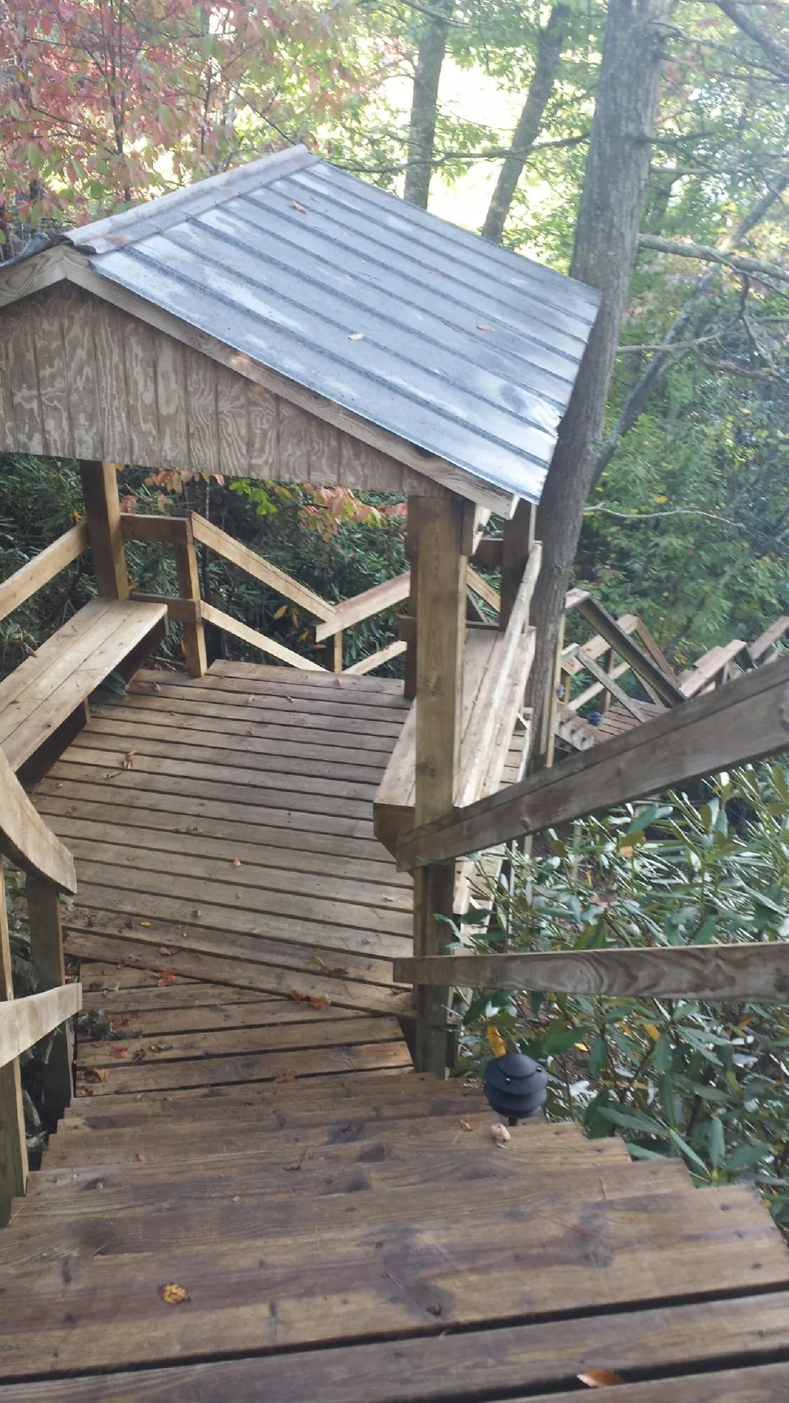 Metal roofed shelter over wooden steps on a wooded walkway — Skylight Repair & Installation work by our crew in Burgettstown