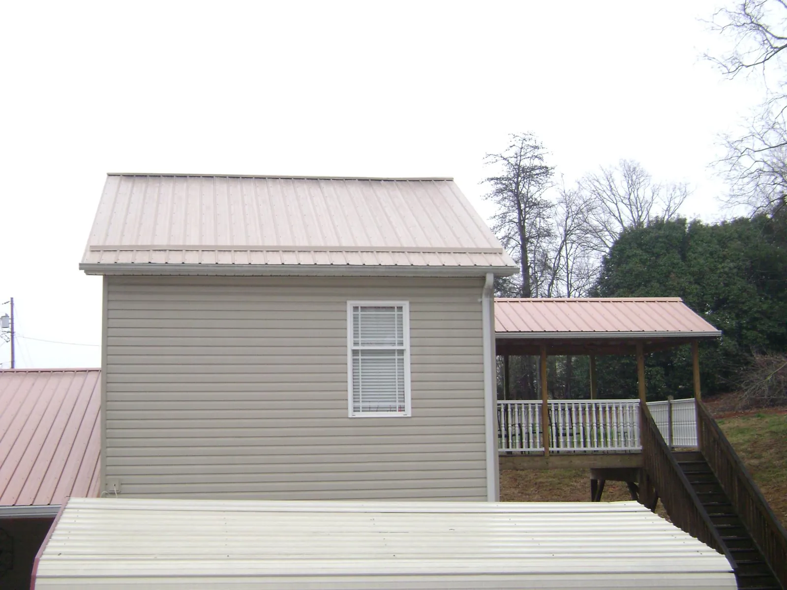 Tan metal roofs on a two story addition and attached porch, from a Roof Replacement job in Burgettstown