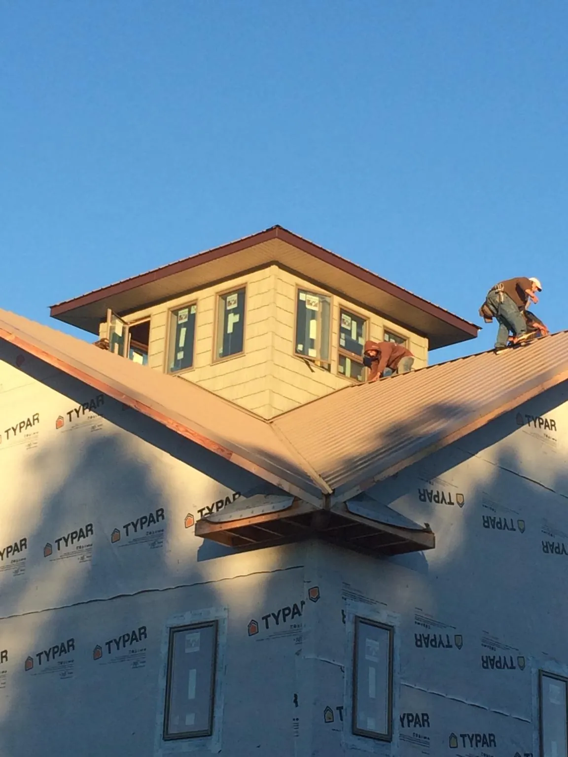 Roofers working around a rooftop cupola on a new metal roof at sunset — Roof Waterproofing in Burgettstown by Roofing Brothers